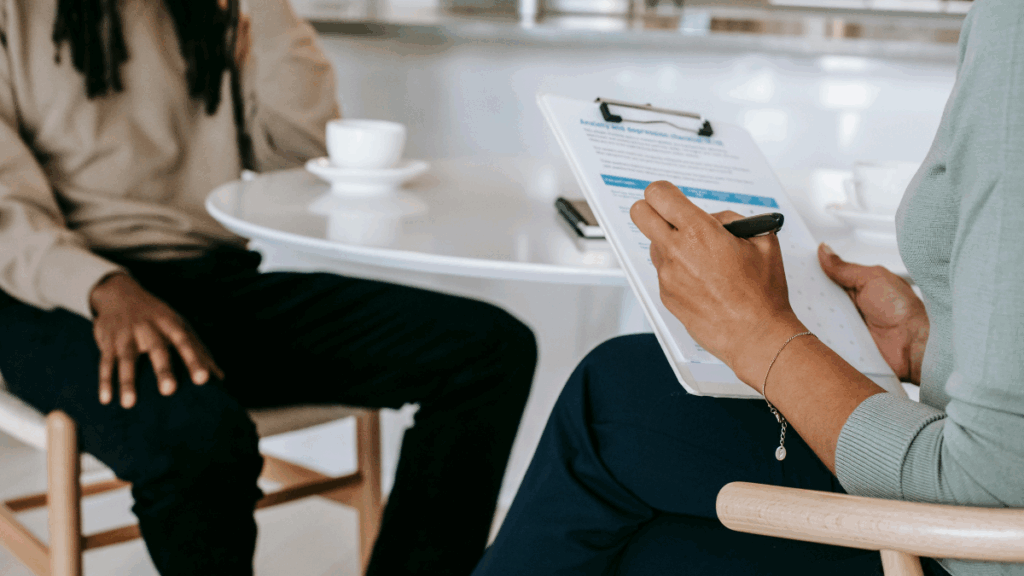 An interviewer writes down interviewee responses on a clipboard.