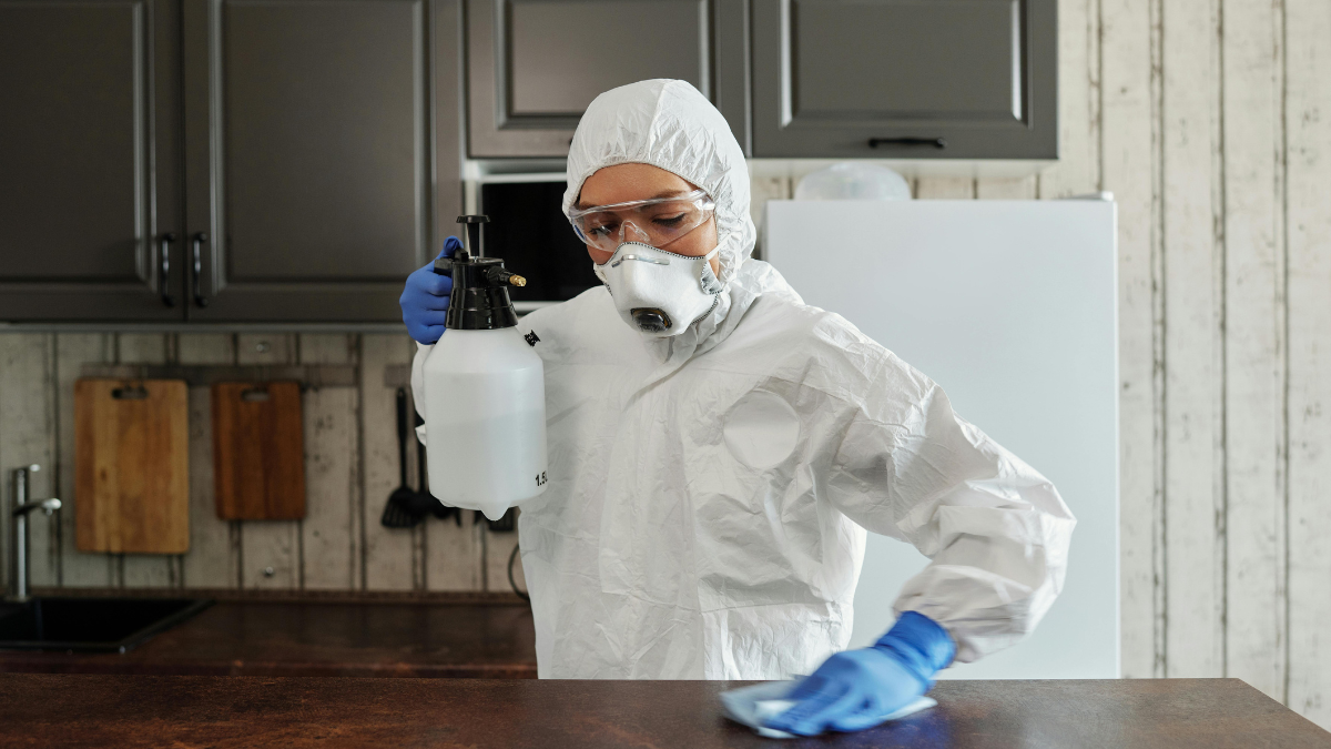 Person in protective gear cleaning a surface with disinfectant spray, symbolizing the myth of needing perfectly clean data for AI.